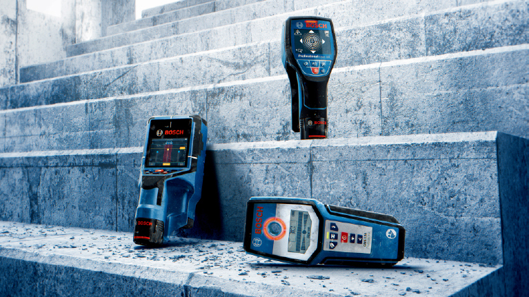 Three Bosch Professional devices are lying on a gray stone staircase.
