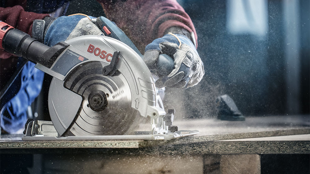 LONG LASTING A Bosch Professional circular saw cuts wood, dust swirls up.