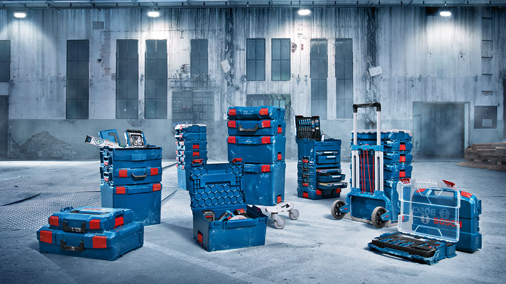 Various blue toolboxes with red elements are standing in an empty gray hall.