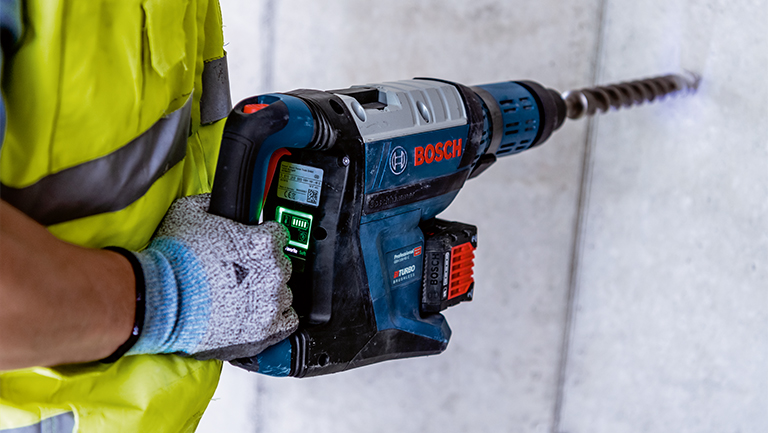 +24 A Bosch Professional cordless hammer drill is held by a person.