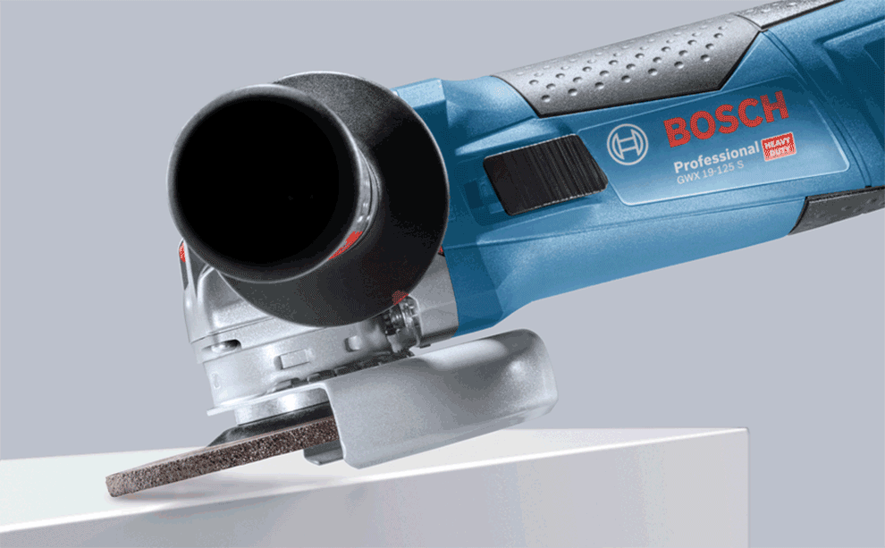 Grinder scrubbing flat A blue Bosch Professional angle grinder is cutting a wooden board.